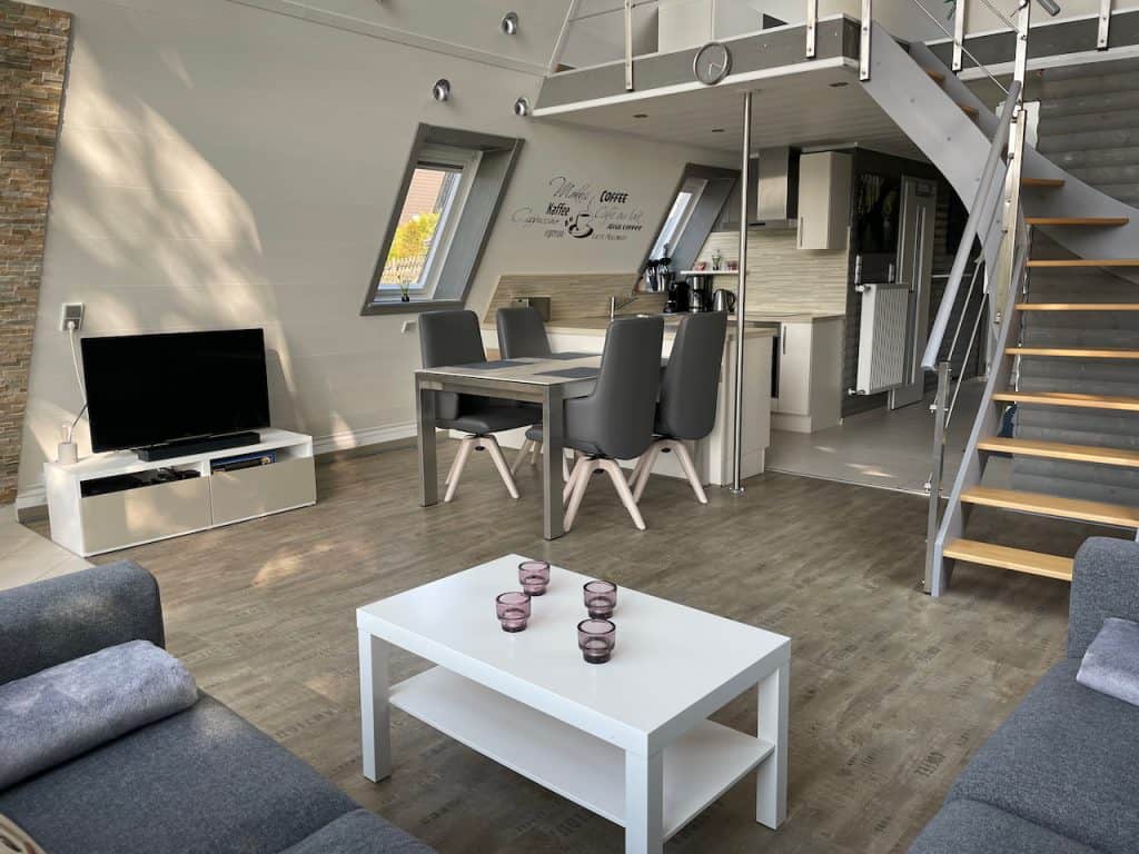Wohnzimmer mit Esstisch, Treppe zur Galerie und Fernseher